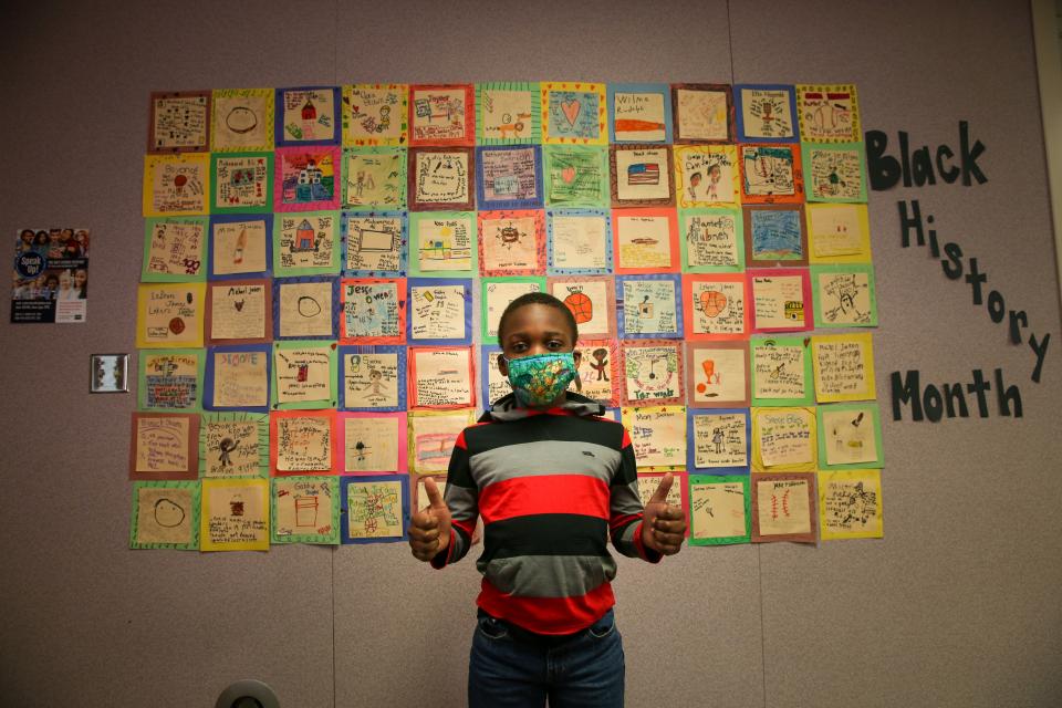 2nd gr. Horizon student gives the thumbs up in front of his class created Black History Month quilt