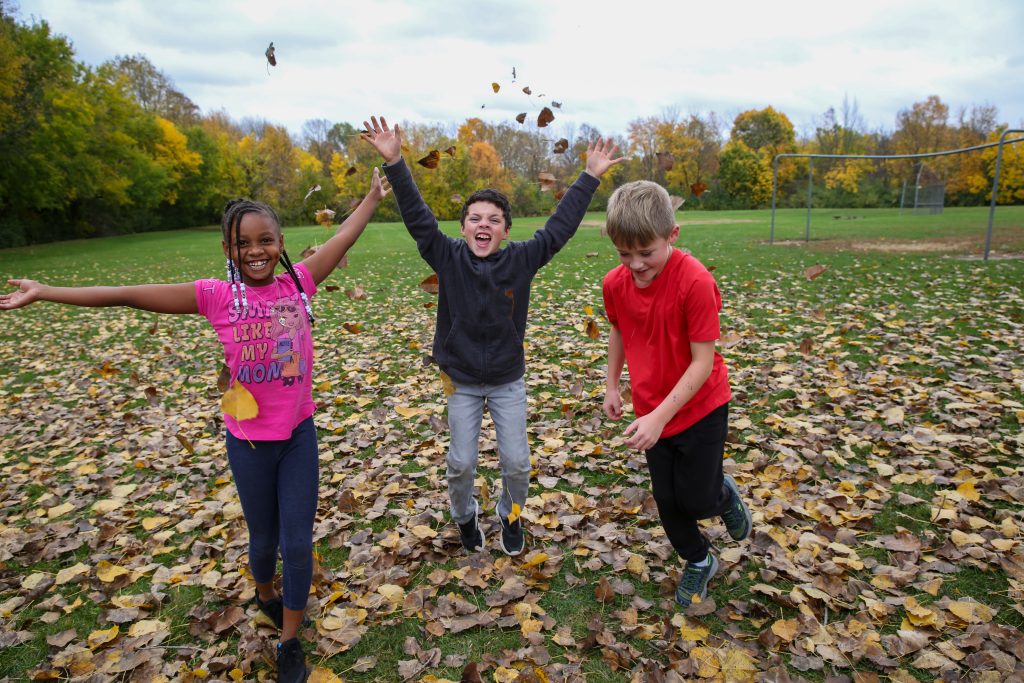 students playin gin the leaves