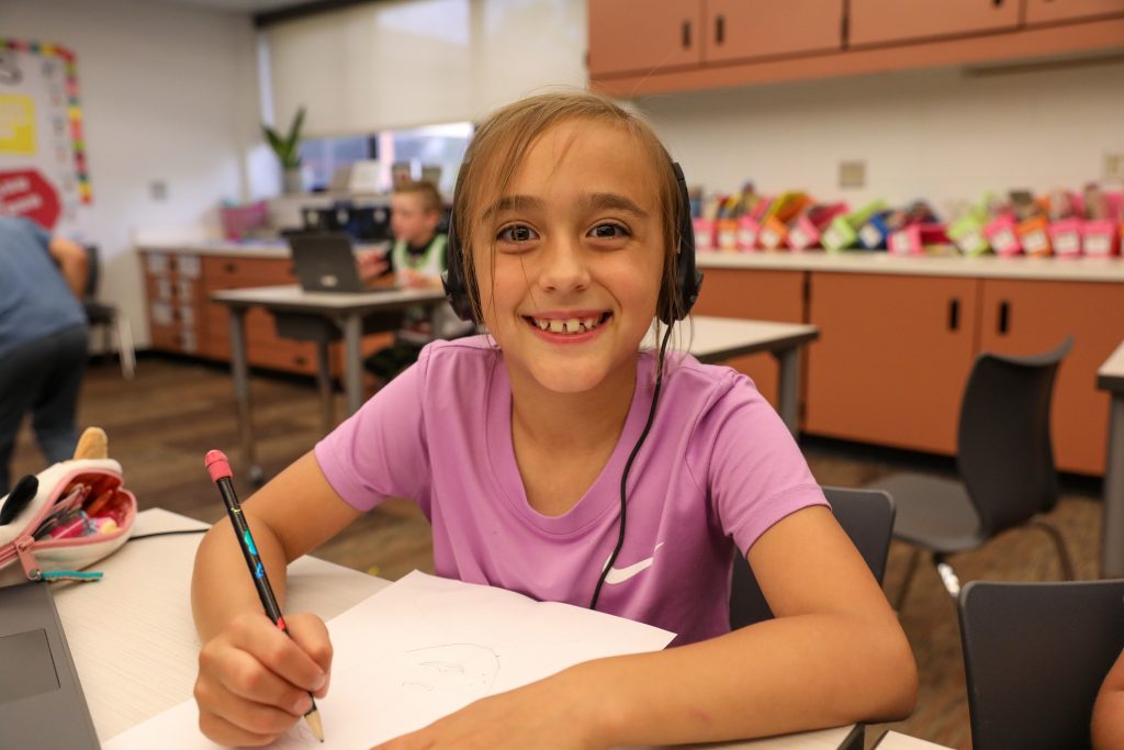 girl smiling while writing on paper