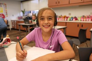 girl smiling while writing on paper