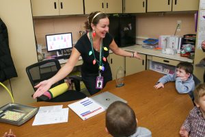 smiling teacher wearing Christmas decorations teaching young students