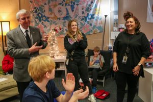 People & students clapping for teacher wearing Christmas decorations