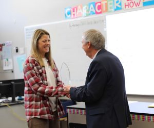 woman in plaid shirt receives award from man in black suit
