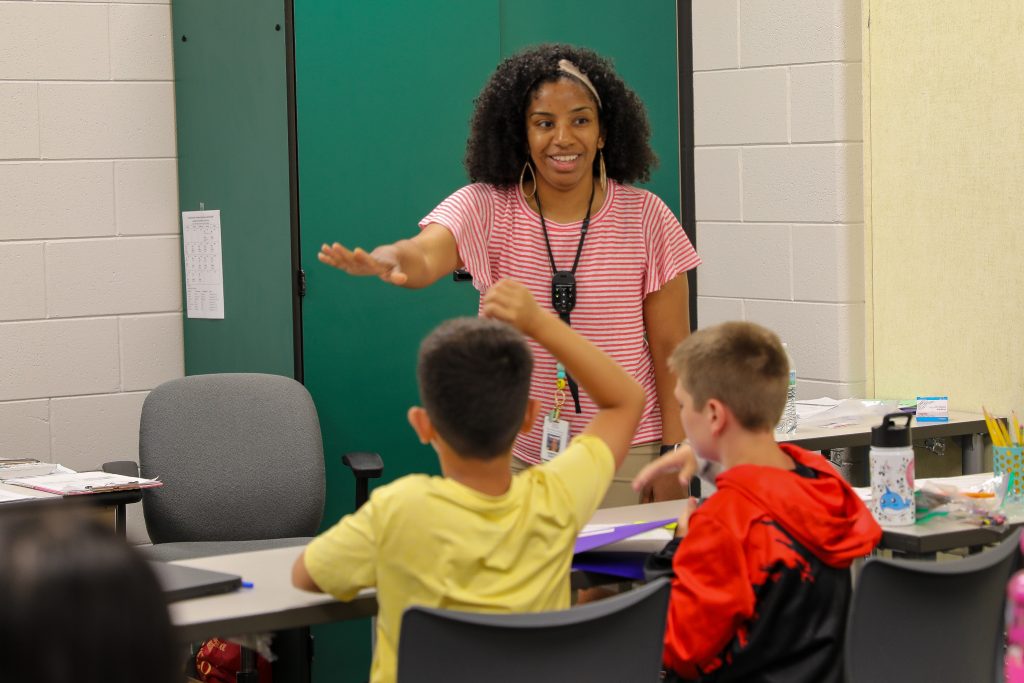 teacher in pink shirt smiling at students