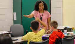 teacher in pink shirt smiling at students