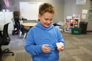 young boy in blue sweatshirt playing with fidget tools