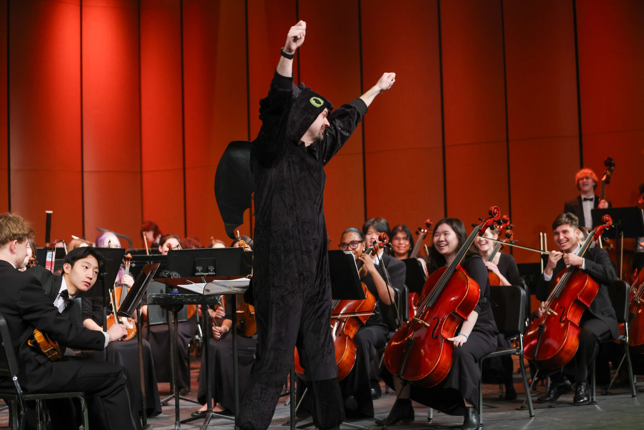 Costumed conductor in front of an orchestra on stage.
