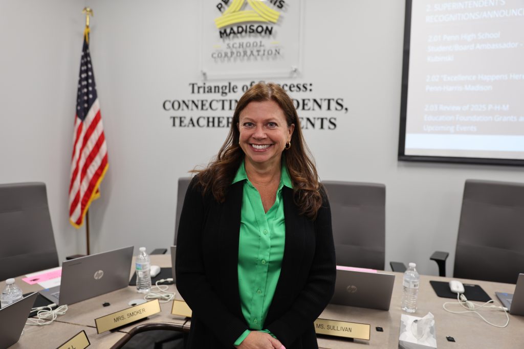 Woman standing in front of a podium at a conference table.