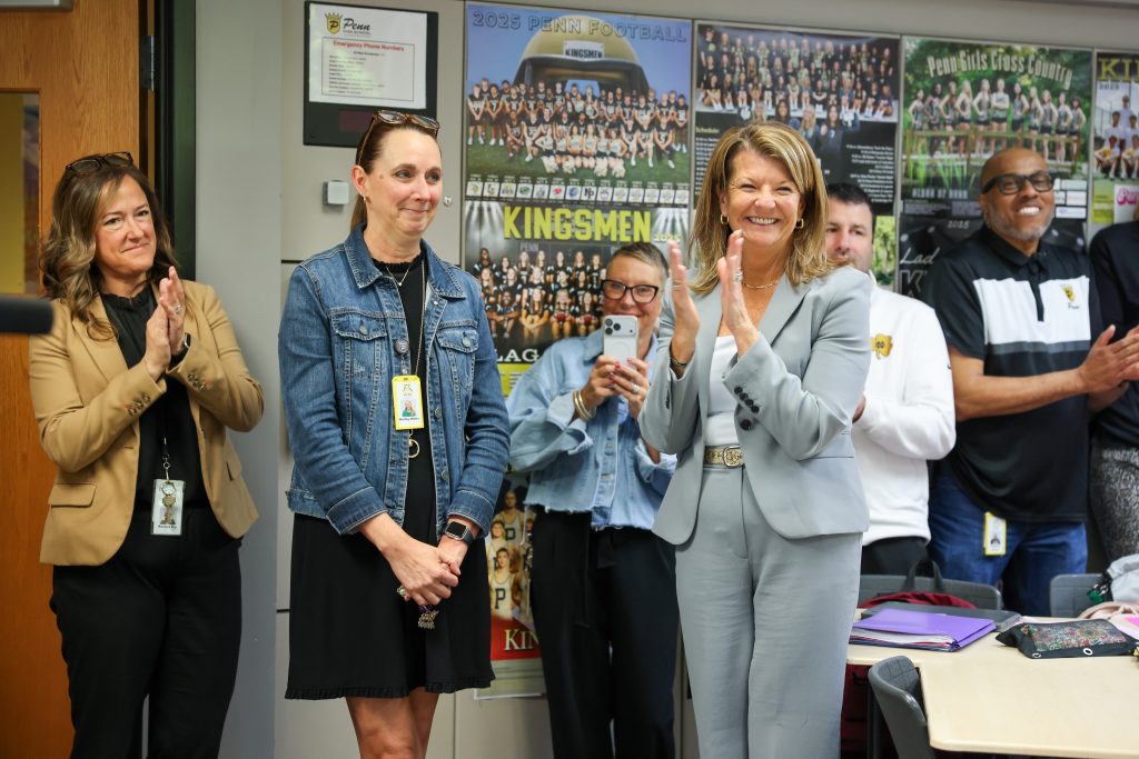 People in a room applauding someone at the front.