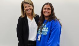 Two women posing for a picture in front of a whiteboard.