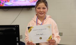 Girl in jacket holding certificate.