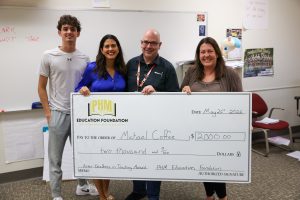 Four people standing in front of a check for $2000, posing for a picture.