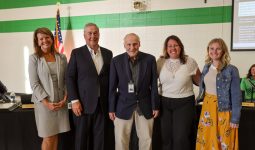 Five people posing together in front of a podium, likely at an event or meeting.