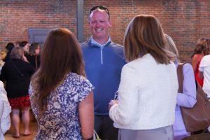 Three people in a room, standing and talking to each other.