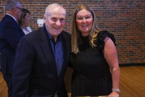 Older man and woman posing together at an event.
