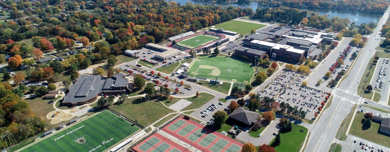 This is an aerial view of a Penn's campus during autumn. The campus is surrounded by trees with fall colors, and there's a river in the background
