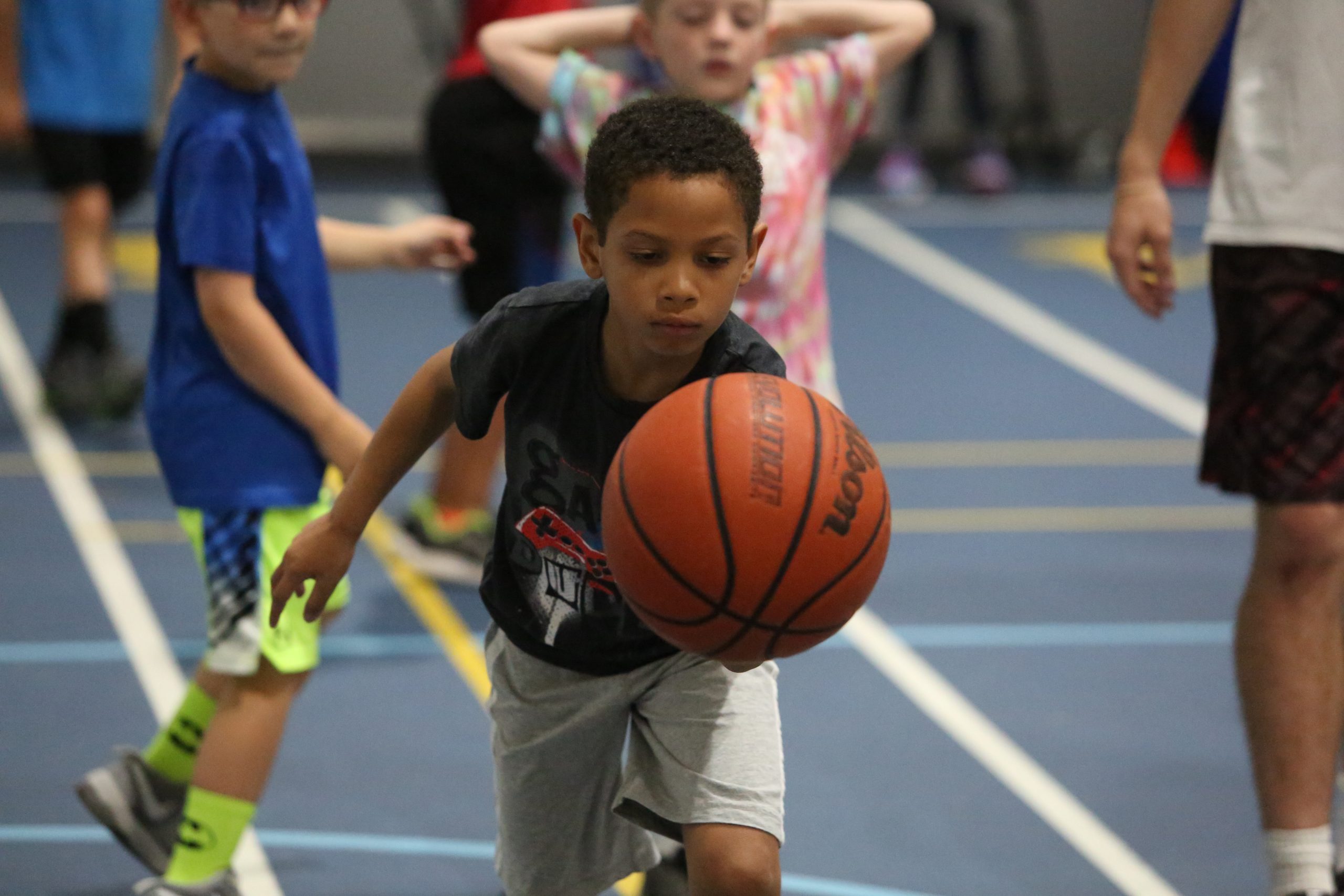 Boy in blue shirt dribbling basketball on court.