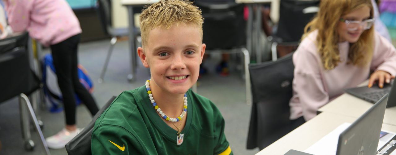 Boy in a classroom setting using a laptop computer.