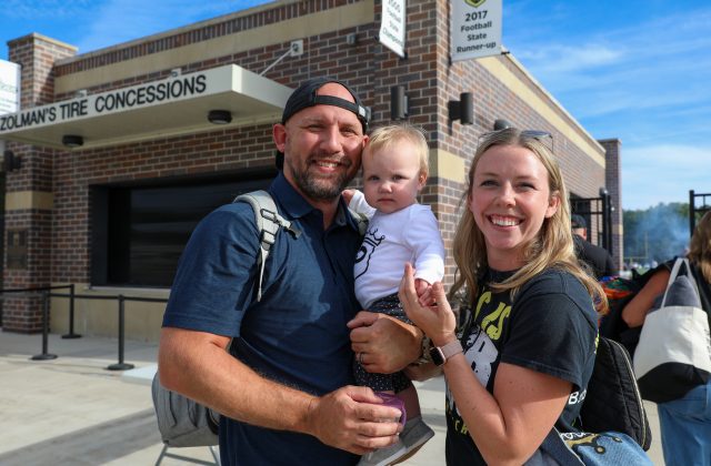 A family posing in front of a building with a sign that reads 'Tire Concessions'.