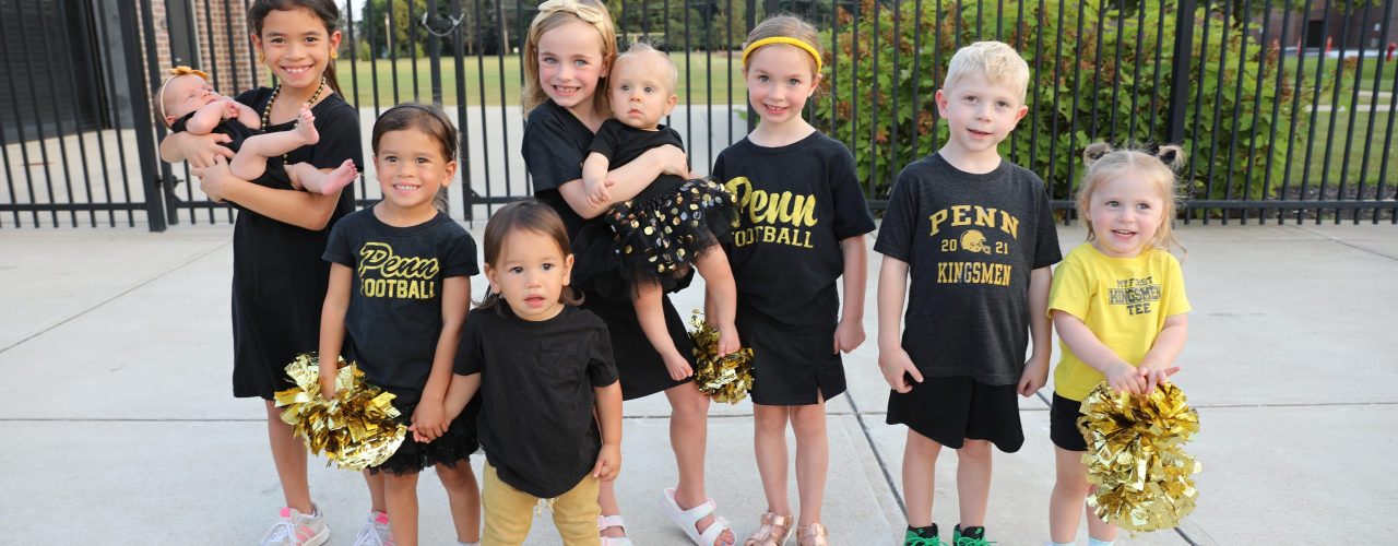 Young cheerleaders posing in front of a fence.