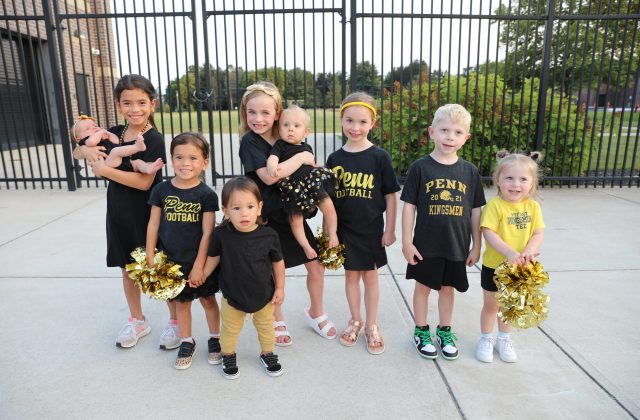 Young cheerleaders posing in front of a fence.