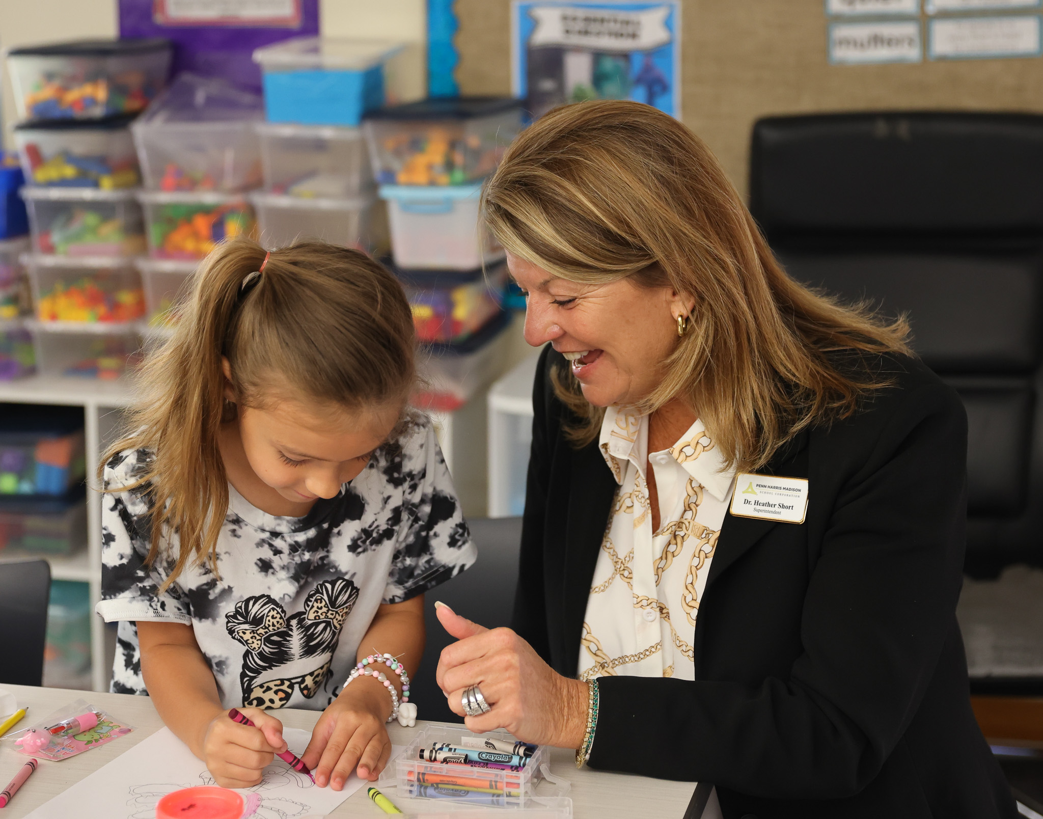 PHM Superintendent Dr. Heather Short sitting with an elementary female student coloring