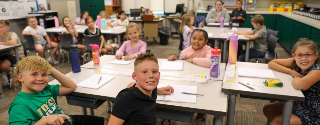 A group of students sitting at desks in a classroom, engaged in an activity