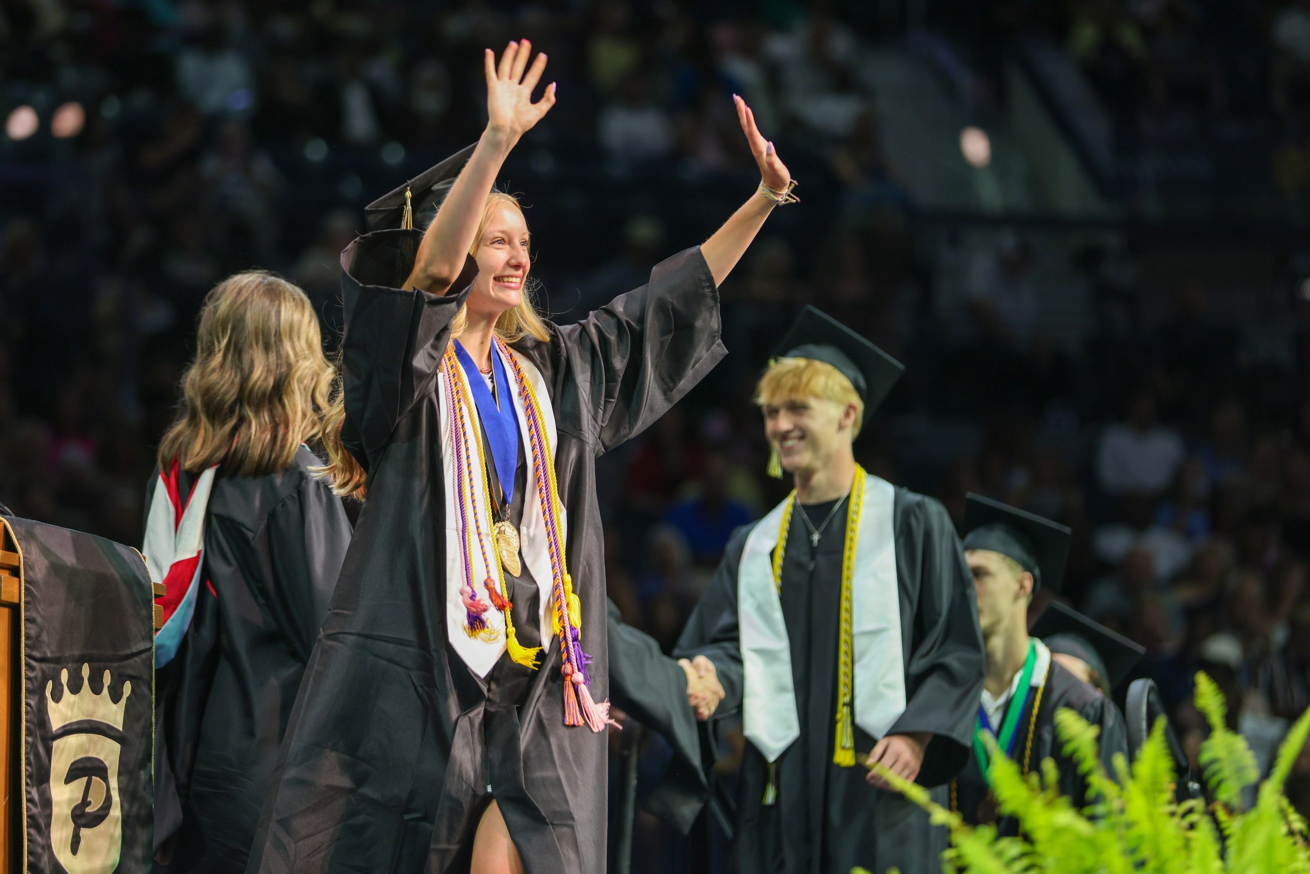 A Penn graduate waving at the crowd as she walks across the stage.